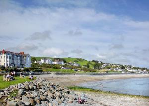 un gruppo di persone seduti su una spiaggia vicino all'acqua di Bron Eifion Lodges a Criccieth
