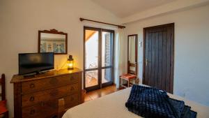 a bedroom with a bed and a dresser with a television at Casa Cielo Mare in Costa Paradiso