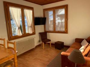 a living room with a couch and a table and windows at Piste B in Morzine