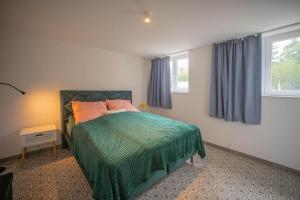 a bedroom with a bed with a green bedspread and two windows at Loft 4 in Schleiden