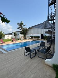 een zwembad met twee stoelen en een parasol bij Villa Soleil, Face a la Mer C1 in Cotonou