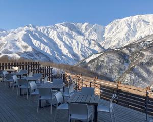 een rij tafels en stoelen op een terras met besneeuwde bergen bij Matsumoto Inn in Matsumoto