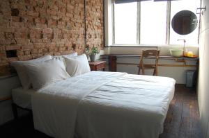 een slaapkamer met een wit bed en een bakstenen muur bij Just House - Rooms & Curios in George Town +13 foto's