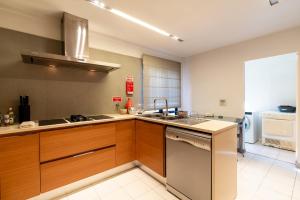 eine Küche mit Holzschränken, einer Spüle und einem Geschirrspüler in der Unterkunft Design Gardens Nº2 in Bicas