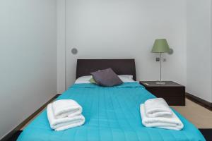 ein Schlafzimmer mit einem blauen Bett mit Handtüchern darauf in der Unterkunft Design Gardens Nº2 in Bicas