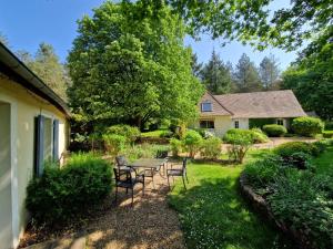 un cortile con tavolo, sedie e una casa di La Chaine a Saint-Jean-du-Bois