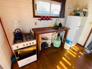 a small kitchen with a stove and a refrigerator at La Fresa glamping in Punta Del Diablo +30 photos