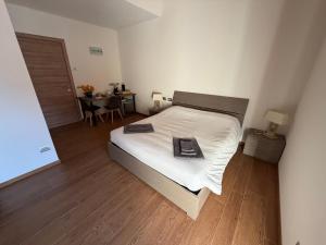 a bedroom with a bed with white sheets and a wooden floor at Ca' Piramidi Casa Vacanze in Postalesio