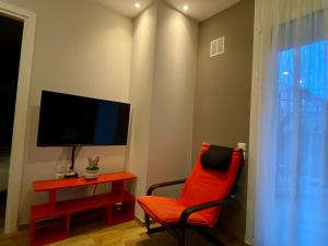 a living room with a red chair and a tv at LUX ONE The Ioannina Residence in Ioannina