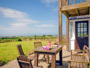 a wooden table with a cake and flowers on it at Rogeston Mount - Cottage in Nolton