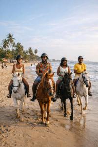 a group of people riding horses on the beach at Château NaNa Willine in Accra