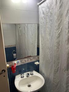 a bathroom with a sink and a white shower curtain at Felicidades in Rosario