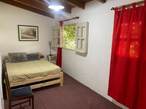 a bedroom with a bed and a window with a red curtain at Felicidades in Rosario