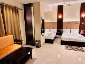 ein Hotelzimmer mit zwei Betten und einer Couch in der Unterkunft Grand Khalifa Hotel Hamama in Sylhet