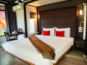 a bedroom with a large bed with red pillows at AKKARA RESORT&VILLA in Chiang Rai