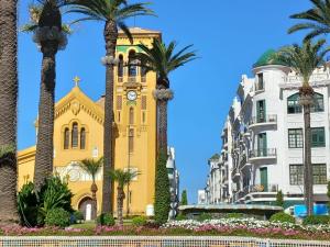 a yellow building with a clock tower and palm trees at Ideal Tetuan in Tétouan