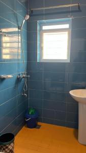 une salle de bain bleue avec une douche et un lavabo dans l'établissement Les Residences Belani - Cadjehoun, Cotonou, à Kika 10 autres photos