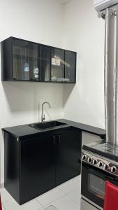 une cuisine noire avec un évier et une cuisinière dans l'établissement Les Residences Belani - Cadjehoun, Cotonou, à Kika