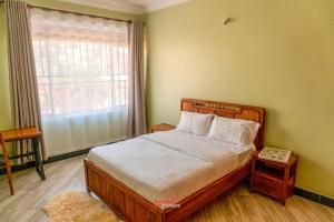a bedroom with a large bed and a window at ExpressFitnessUG in Jinja
