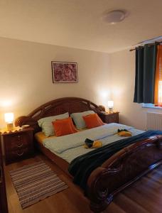ein Schlafzimmer mit einem großen Holzbett mit orangefarbenen Kissen in der Unterkunft Apartman Josip in Gospić