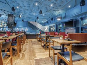 ein Restaurant mit blauen Wänden, Holztischen und Stühlen in der Unterkunft Hotel Belmont Vancouver - MGallery Collection in Vancouver