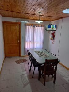 a dining room with a table and chairs and a door at Cabañas San Benito in Los Antiguos
