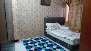 a small bedroom with a bed and a checkered floor at el-yusra homestay in Bayan Lepas