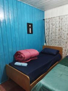 een kamer met een bed met een blauwe muur bij Quarto N II Cama casal e uma de solteiro in Gramado