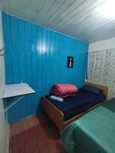 een blauwe kamer met een bed met een rood kussen bij Quarto N II Cama casal e uma de solteiro in Gramado +3 foto's