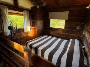 a bedroom with a striped bed in a cabin at Cabañas El Atalaya in Villa Rumipal