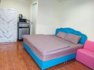 una cama con cabecero azul y una silla rosa en Nopphadon Hotel, en Lat Krabang