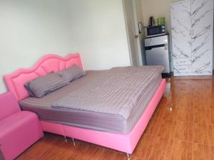 Una cama con un marco de cama rosa en una habitación. en Nopphadon Hotel, en Lat Krabang 17 fotos más