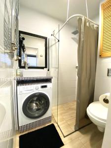 een wasmachine in de badkamer met een spiegel bij Lemuria Studio Łokietka in Legnica