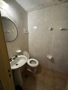 een badkamer met een wastafel, een toilet en een spiegel bij Piemonte in Mar del Plata