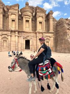 a woman riding a horse in front of a building at Nadina Bedouin home in Petra