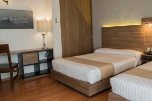 a hotel room with two beds and a desk at Hotel Villa Del Sol Expo in Guadalajara