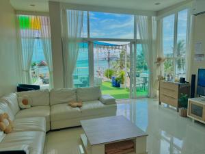 Una sala de estar con un sofá y vista al mar. en Seaview pool villa bangsaray, en Bang Sare