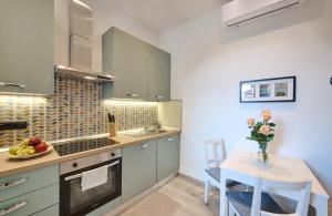 a kitchen with green cabinets and a table with a vase of flowers at La cà del Pin in Lierna