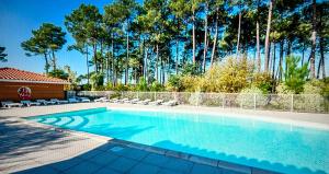 a swimming pool with chairs and a fence at Charmante villa in Parentis-en-Born
