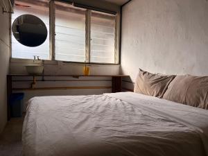 een slaapkamer met een bed, een wastafel en een spiegel bij Just House - Rooms & Curios in George Town