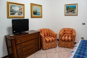 a bedroom with a tv and a chair and a dresser at Appartamento Clivo in Solto Collina
