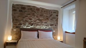 een slaapkamer met een bed met een stenen muur bij Comelico CasaVacanza in Santo Stefano di Cadore