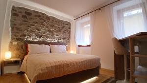 een slaapkamer met een bed met een stenen muur bij Comelico CasaVacanza in Santo Stefano di Cadore