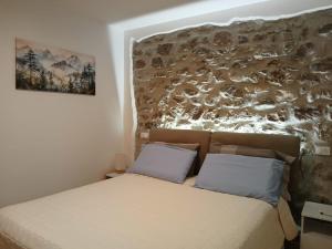 een bed met 2 kussens in een kamer met een muur bij Comelico CasaVacanza in Santo Stefano di Cadore