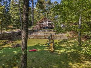 een speeltuin in een tuin met een huis op de achtergrond bij Tall Pines Lodge in Eagle River WI in Eagle River