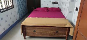 ein Schlafzimmer mit einem Bett mit rosa Kissen darauf in der Unterkunft Block White Town Home Stay in Puducherry