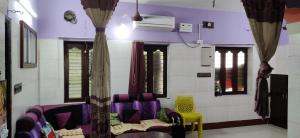 ein Wohnzimmer mit lila Stühlen und Fenstern in der Unterkunft Block White Town Home Stay in Puducherry
