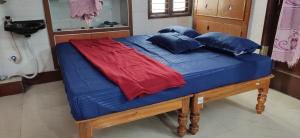ein blaues Bett mit einer roten Decke und blauen Kissen in der Unterkunft Block White Town Home Stay in Puducherry