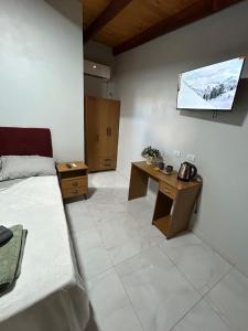 ein Zimmer mit einem Bett, einem Schreibtisch und einem Fernseher in der Unterkunft Cabañas Luna 