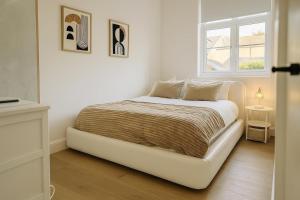 een wit bed in een witte kamer met een raam bij Louisville Flat 3 in Newmarket